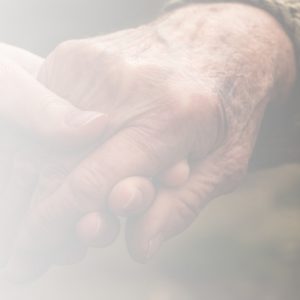 An older person's hand being held gently by a younger person's hand
