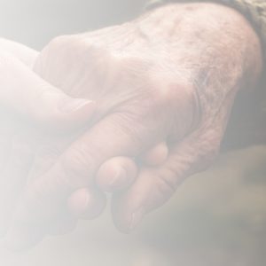 An older person's hand being held gently by a younger person's hand