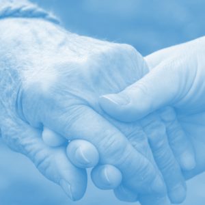 An older person's hand being held gently by a younger person's hand