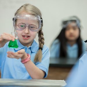 Primary school girl with Down Syndrome does chemistry experiment in school science lab