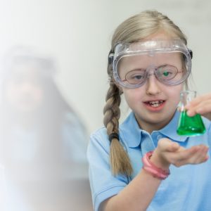 Primary school girl with Down Syndrome does chemistry experiment in school science lab